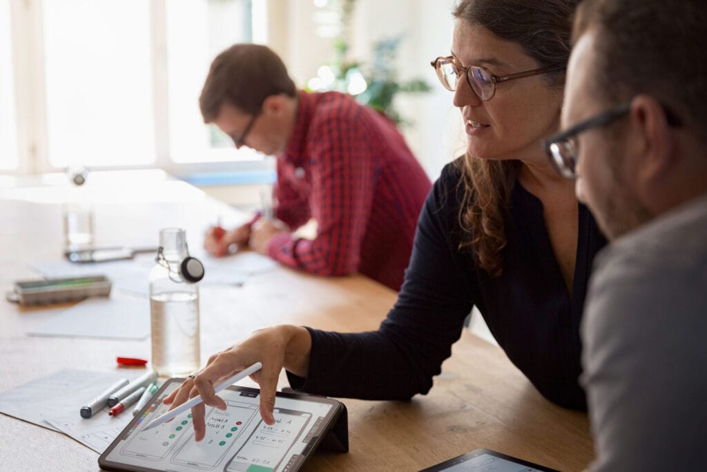 Das UX Team welches ein Prototype diskutiert auf einem iPad